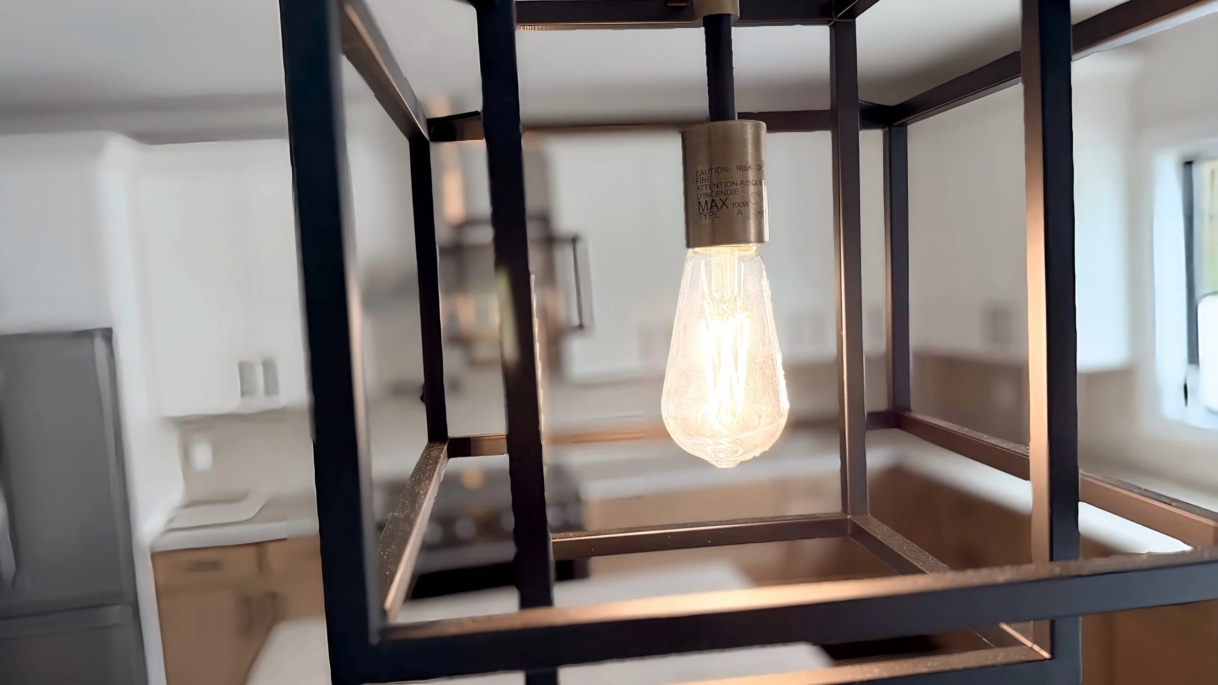 Close-up of a lit Edison-style light bulb within a black metal frame or cage.