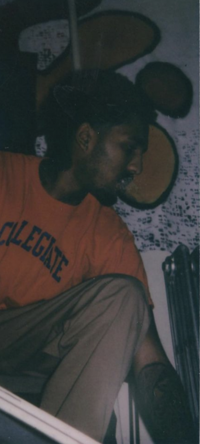A man with long hair and a beard, wearing an orange