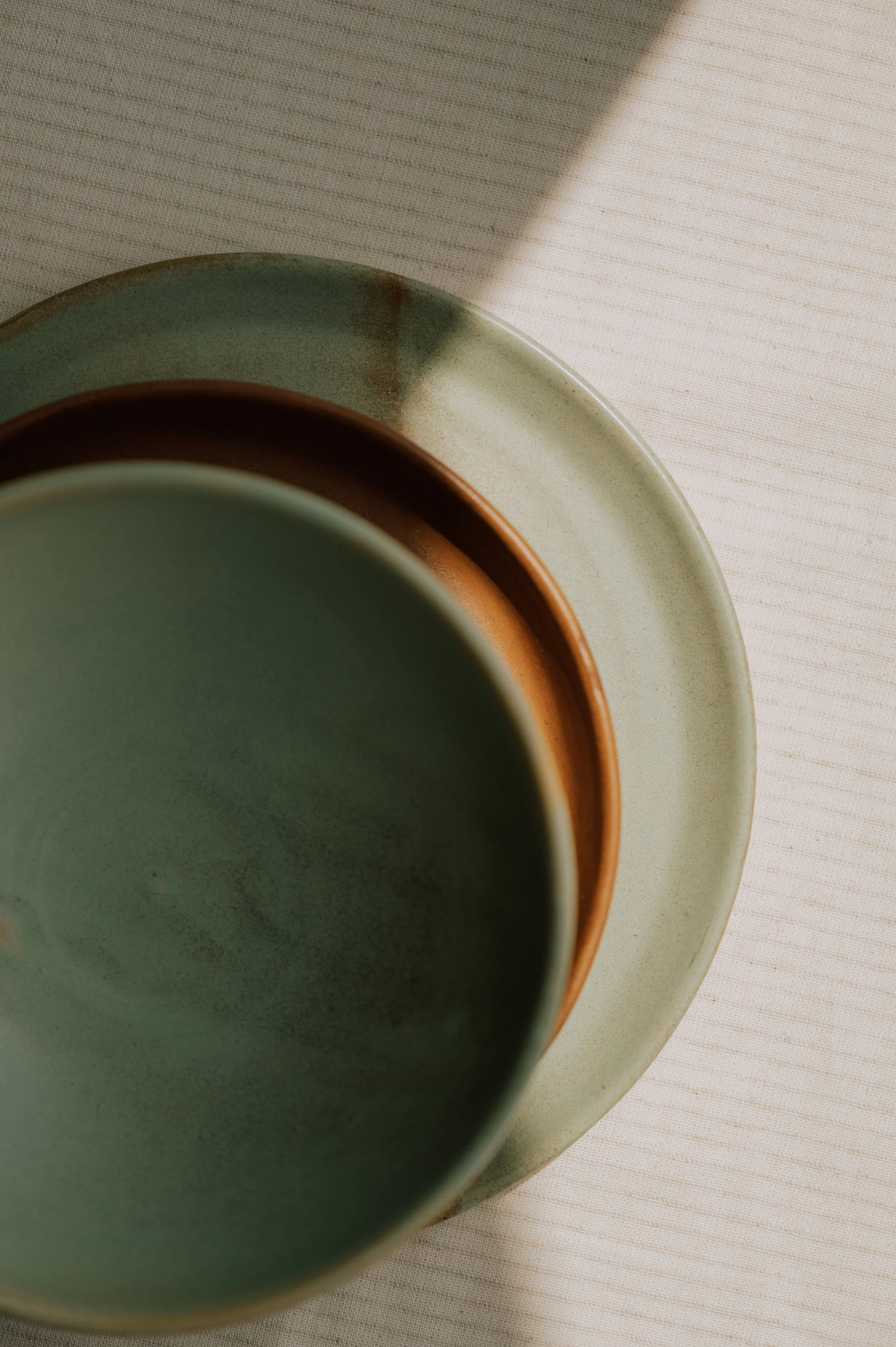 Matte sage green ceramic bowl displayed on a neutral linen surface with minimalist tableware.
