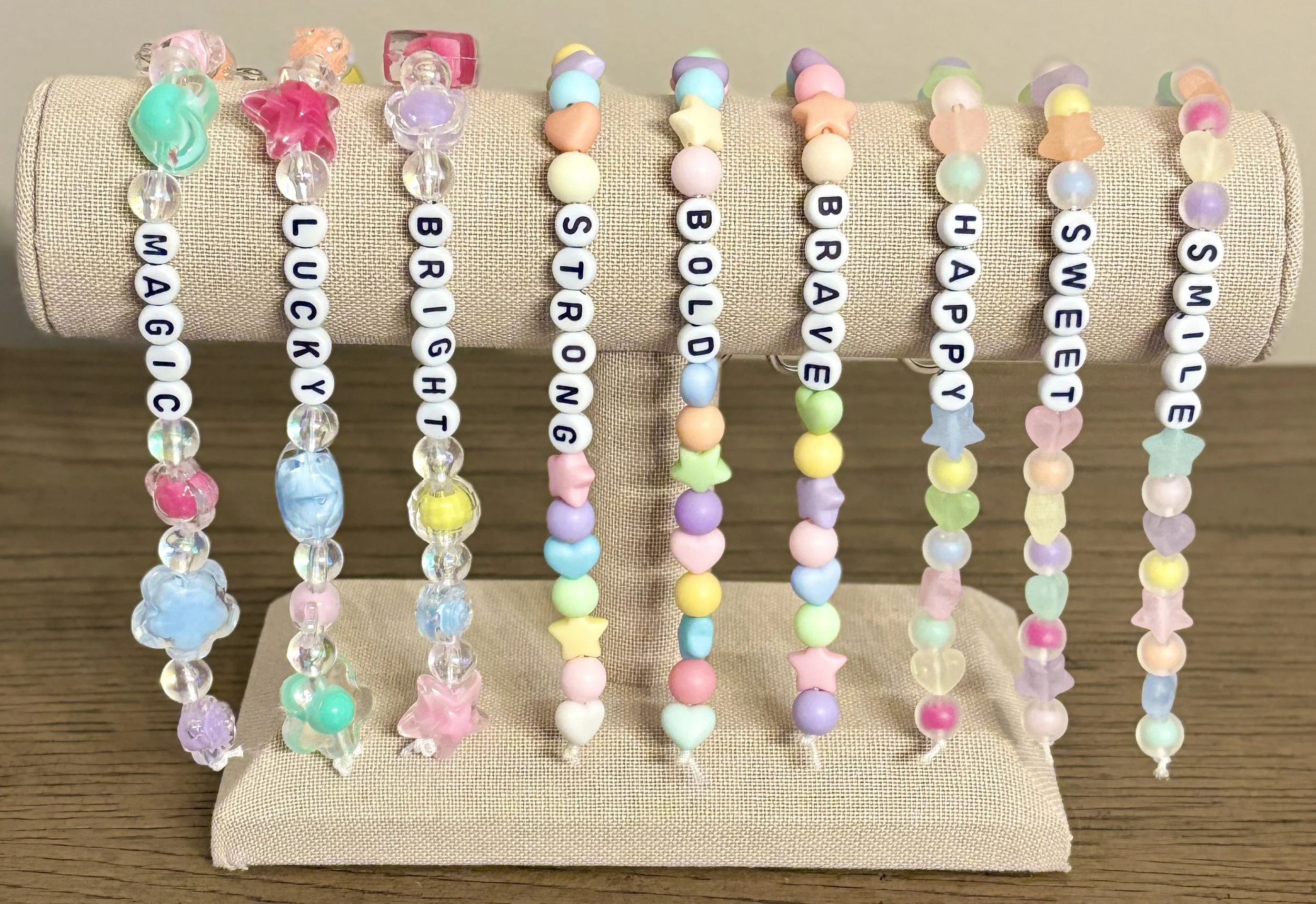 Colorful bead necklaces displayed on a beige padded stand on a wooden surface.