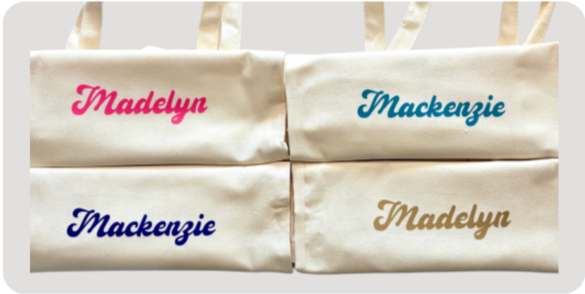 Four fabric bags with names embroidered on them: two with the name Madelyn in pink and gold, and two with the name Mackenzie in blue and navy.