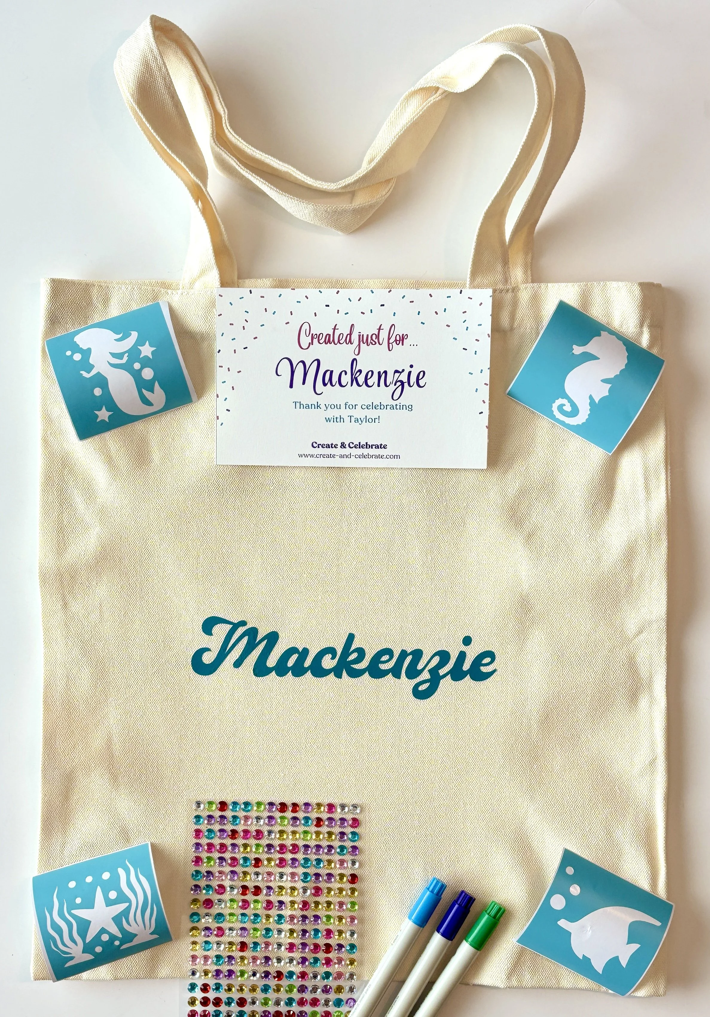 A personalized gift bag with a thank you note for Mackenzie, decorated with ocean-inspired stickers of a mermaid tail, seahorse, starfish, and whale, along with colorful rhinestones and markers.