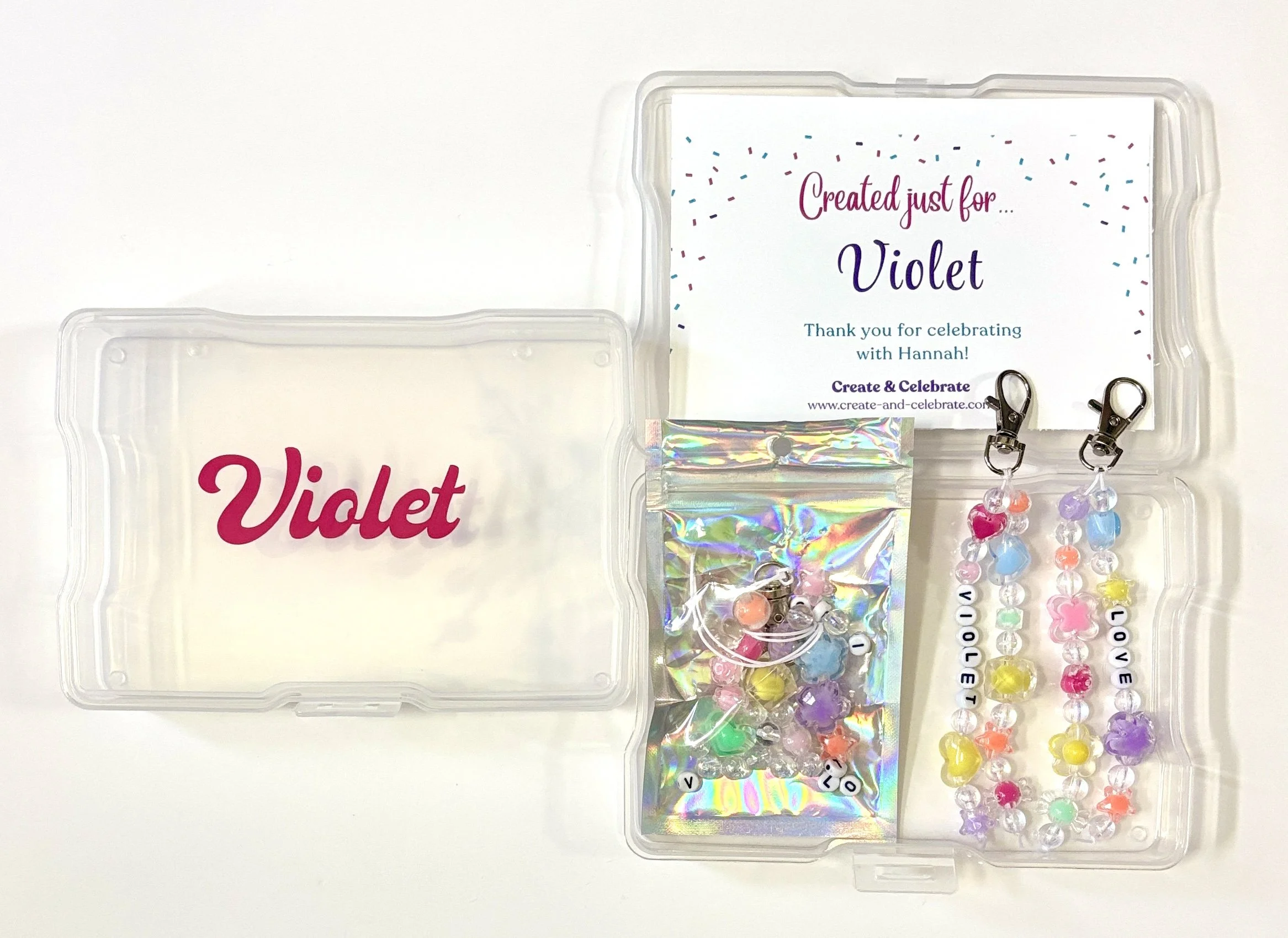 A clear plastic container holding colorful beads with letters and charms, alongside a label reading "Created just for... Violet" and a message thanking for celebrating with Hannah.