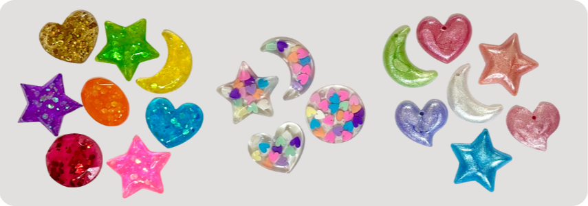 Colorful charms shaped like hearts, stars, moons, and circles with glitter and confetti designs.