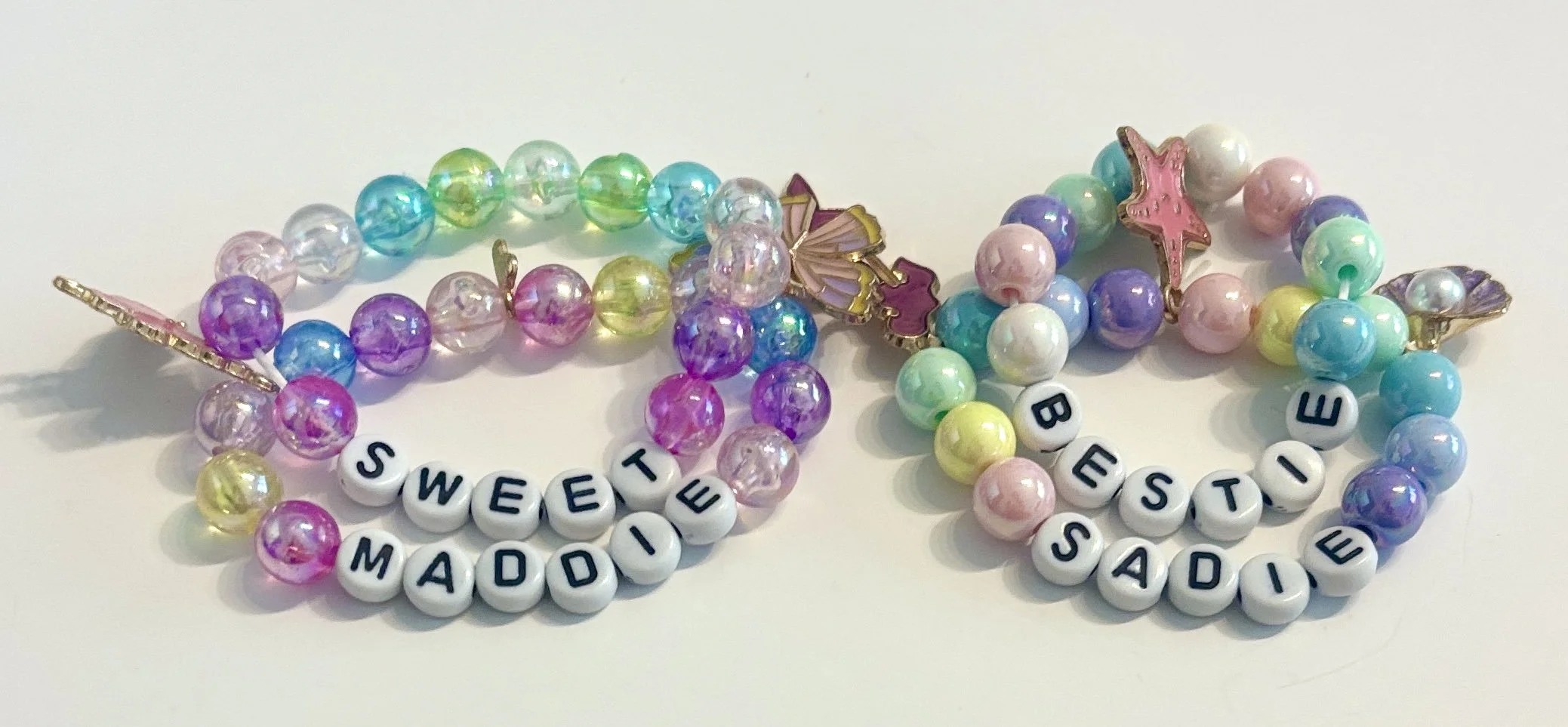 Colorful beaded bracelets with letter beads spelling 'SWEET MAD' and 'E SISTE SAD' on a white background.