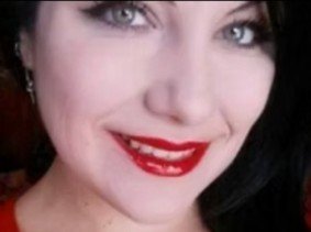 Close-up of a woman with dark hair, red lipstick, and a bright smile.