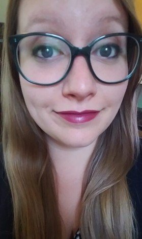 Close-up of a woman with glasses and long, light brown hair.
