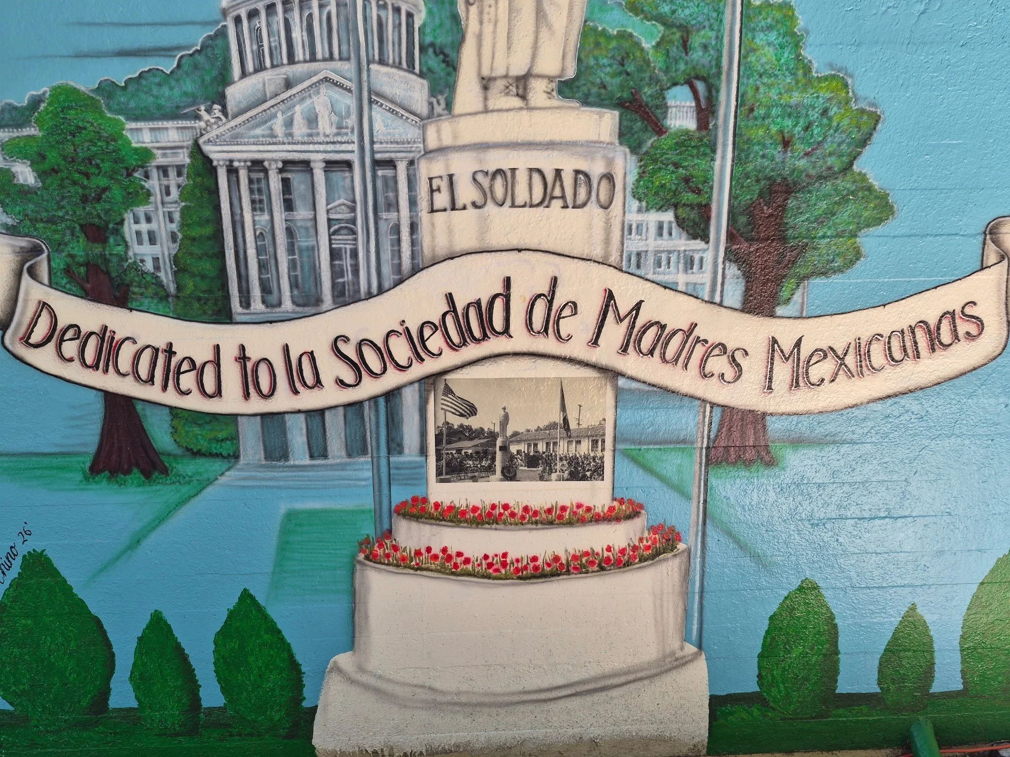 A mural depicting a monument with the word 'EL SOLDADO,' surrounded by trees and a banner with the phrase 'dedicated to the society of Madrid, Mexico.'