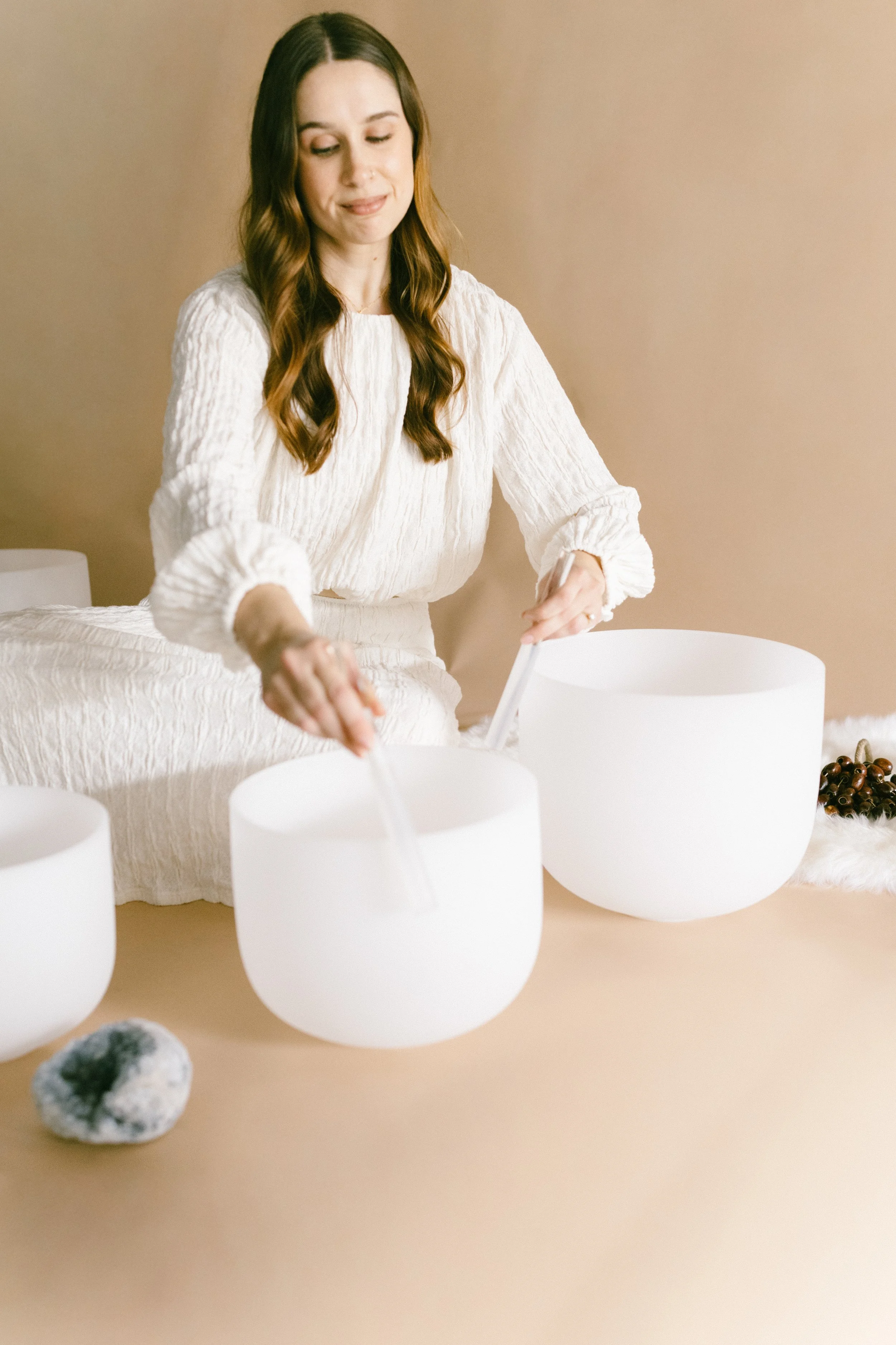 Hannah playing two crystal singing bowls during a sound bath.