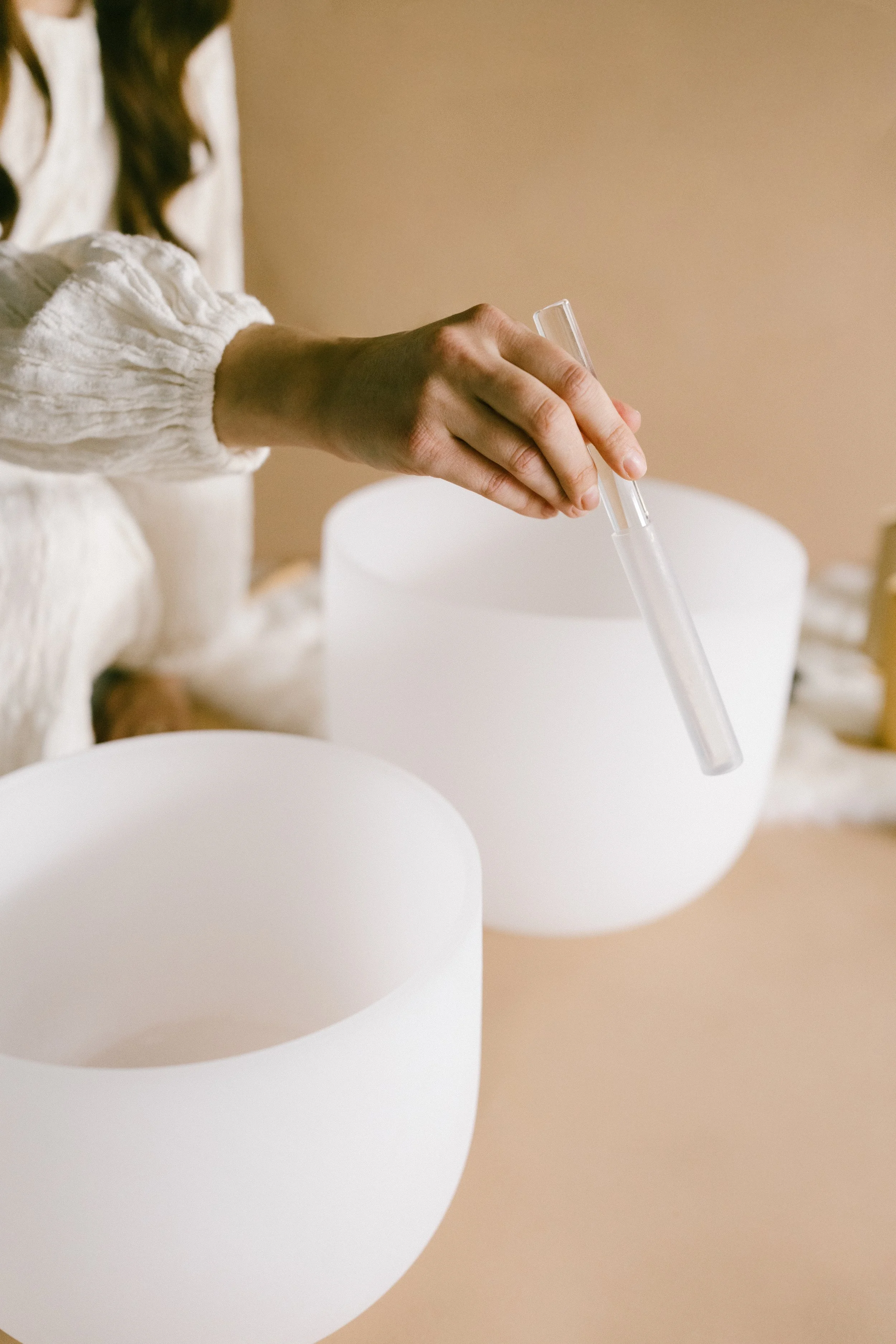 Hand playing a crystal singing bowl during a sound bath.