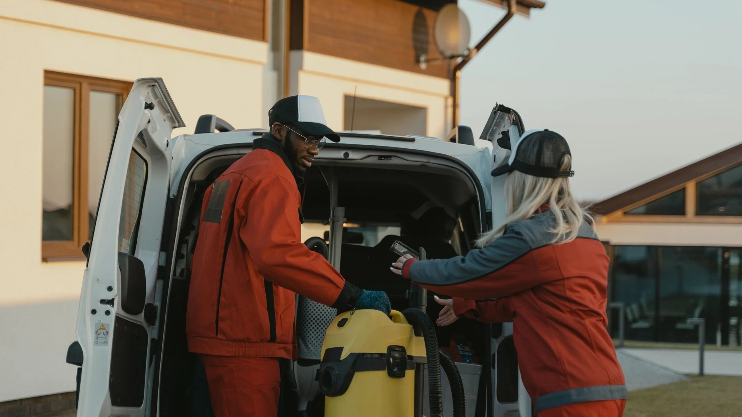 Two emergency medical responders loading medical equipment into an ambulance outside a building.