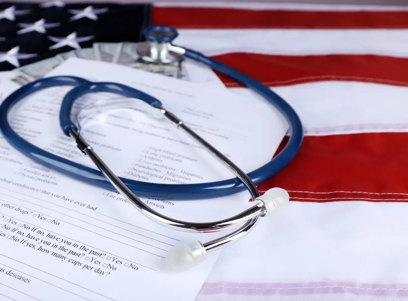 A stethoscope and a medical questionnaire resting on an American flag.