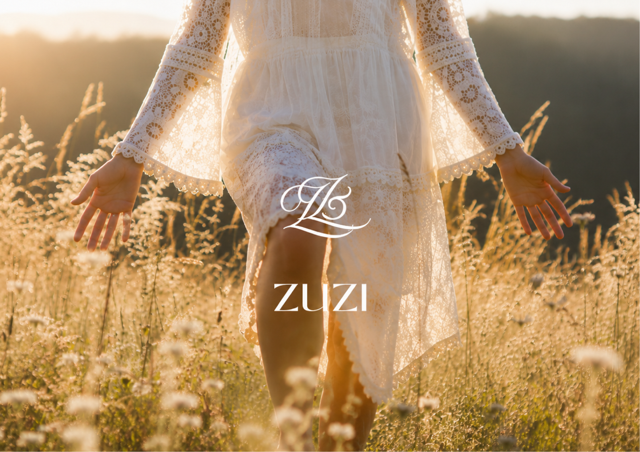 A person wearing a white lace dress standing in a field of tall grass and wildflowers during sunset, with holding the dress slightly lifted. The image has the words "ZUZI" written in white at the bottom.