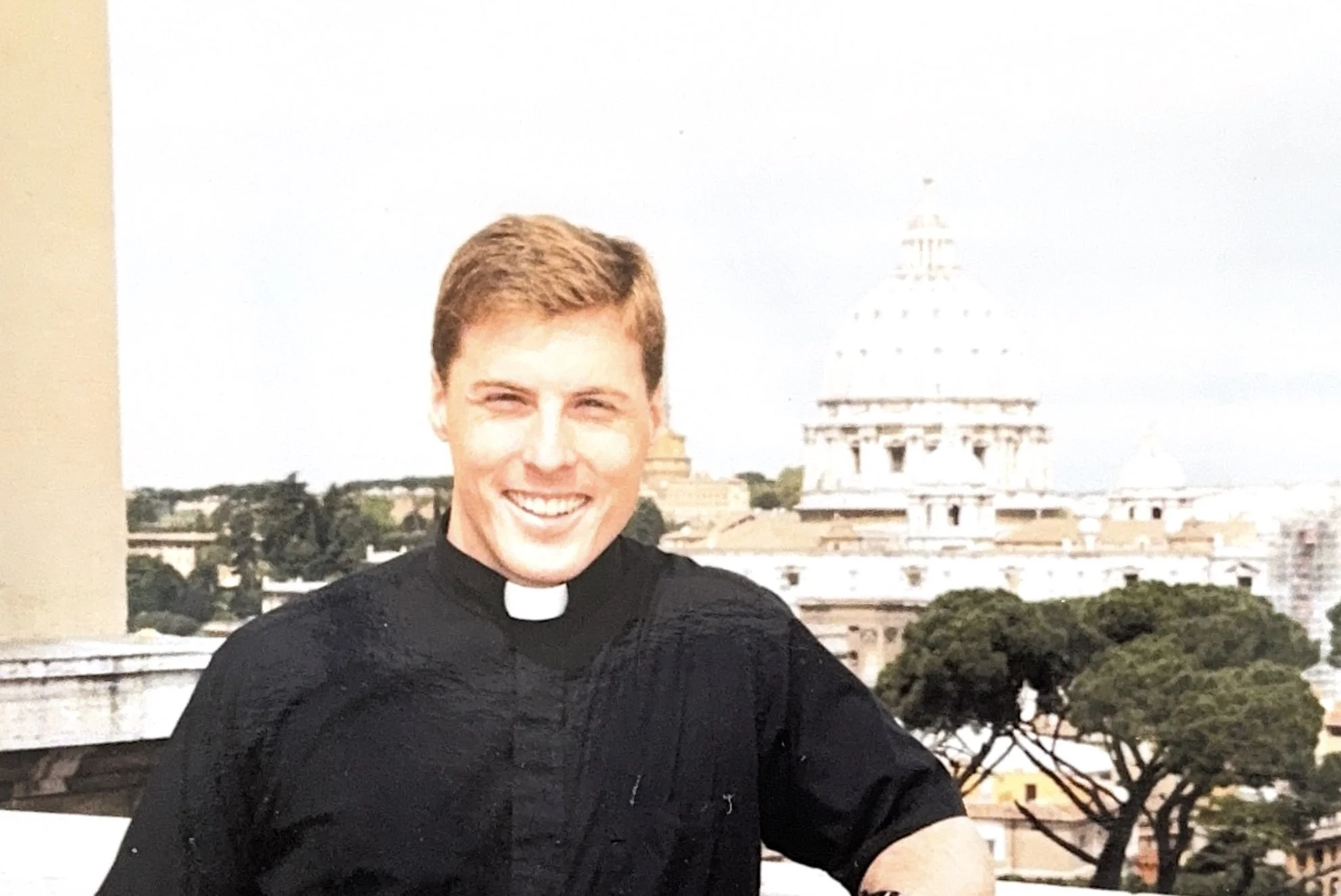 Bill Hambleton as a seminarian in Roman collar, with St. Peter's Basilica in the background