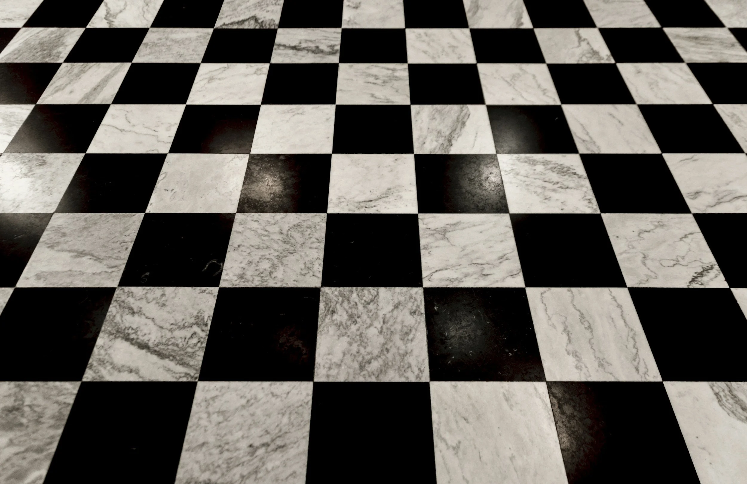Close-up view of a black and white checkered marble floor with alternating dark and light tiles.