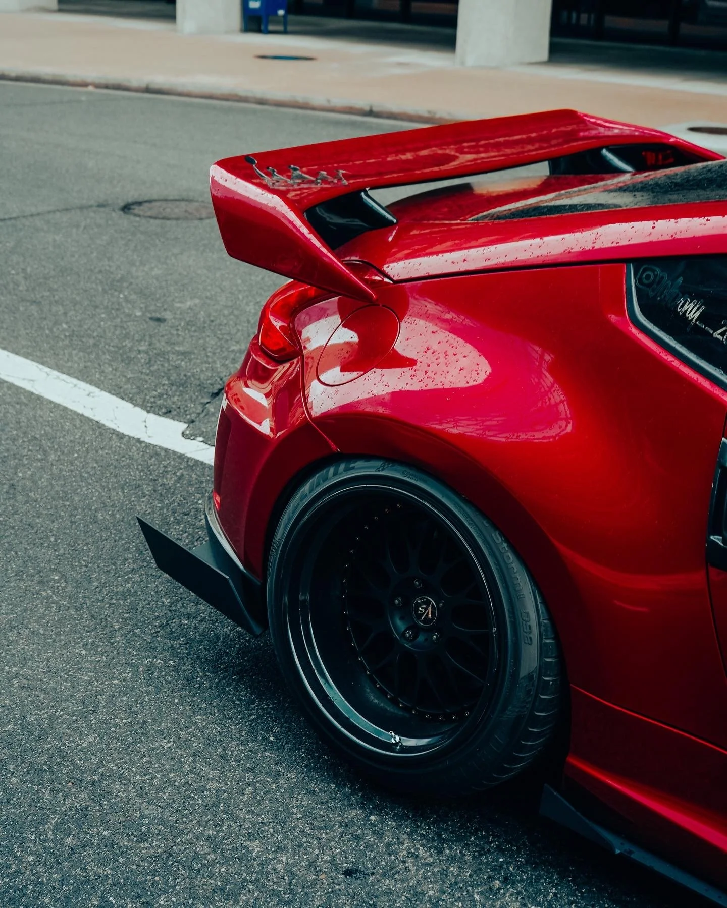 Close-up of the rear of a red sports car with a black rear wheel and a large rear wing.