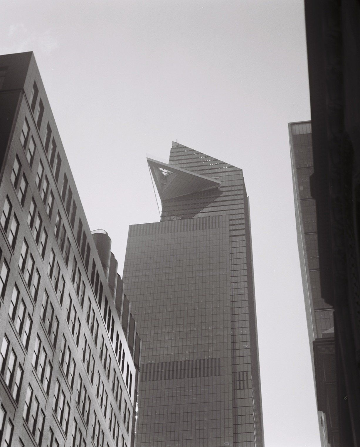 Black and white photo of tall skyscrapers from a street-level perspective in an urban city.