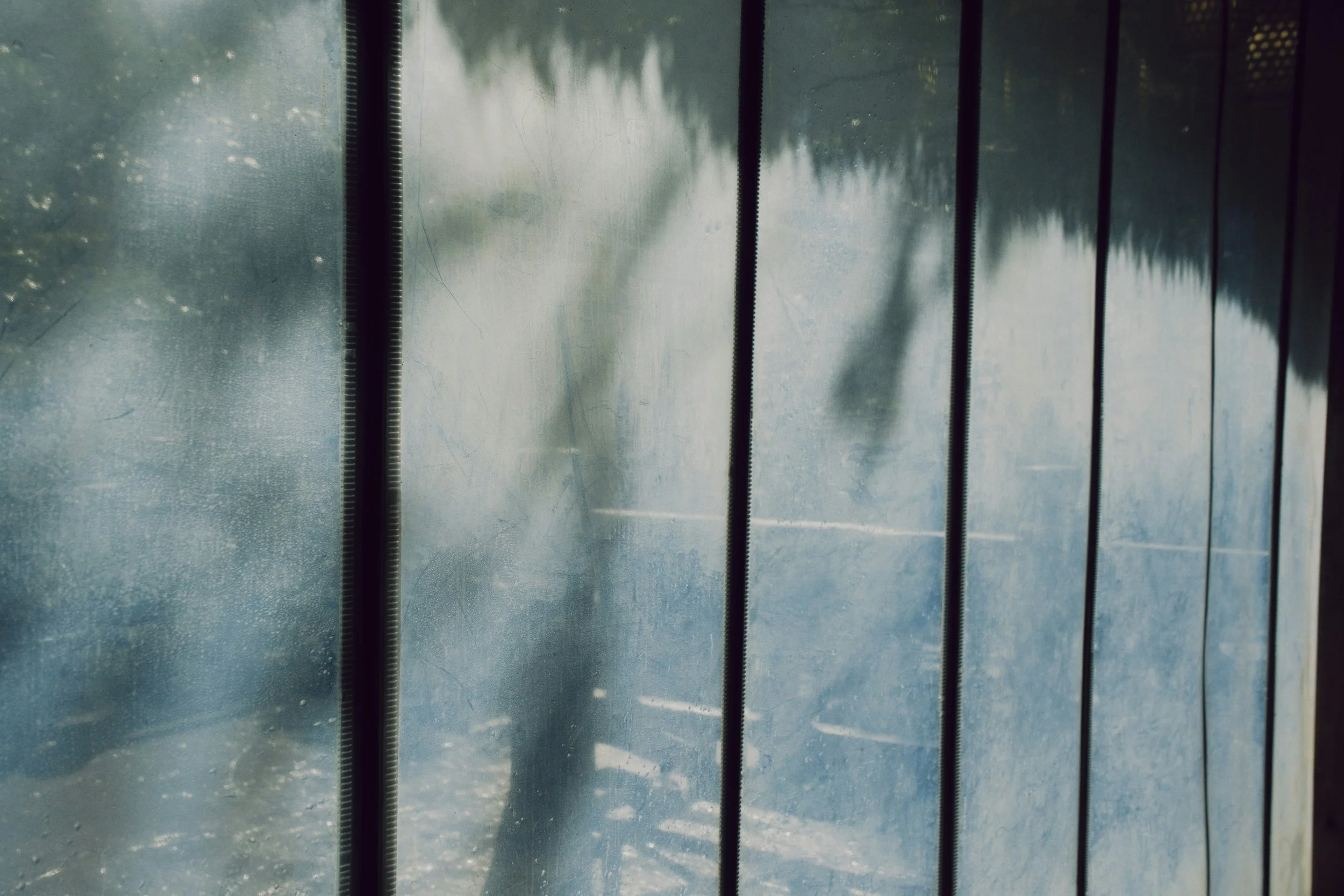 Rain falling outside a window with blinds