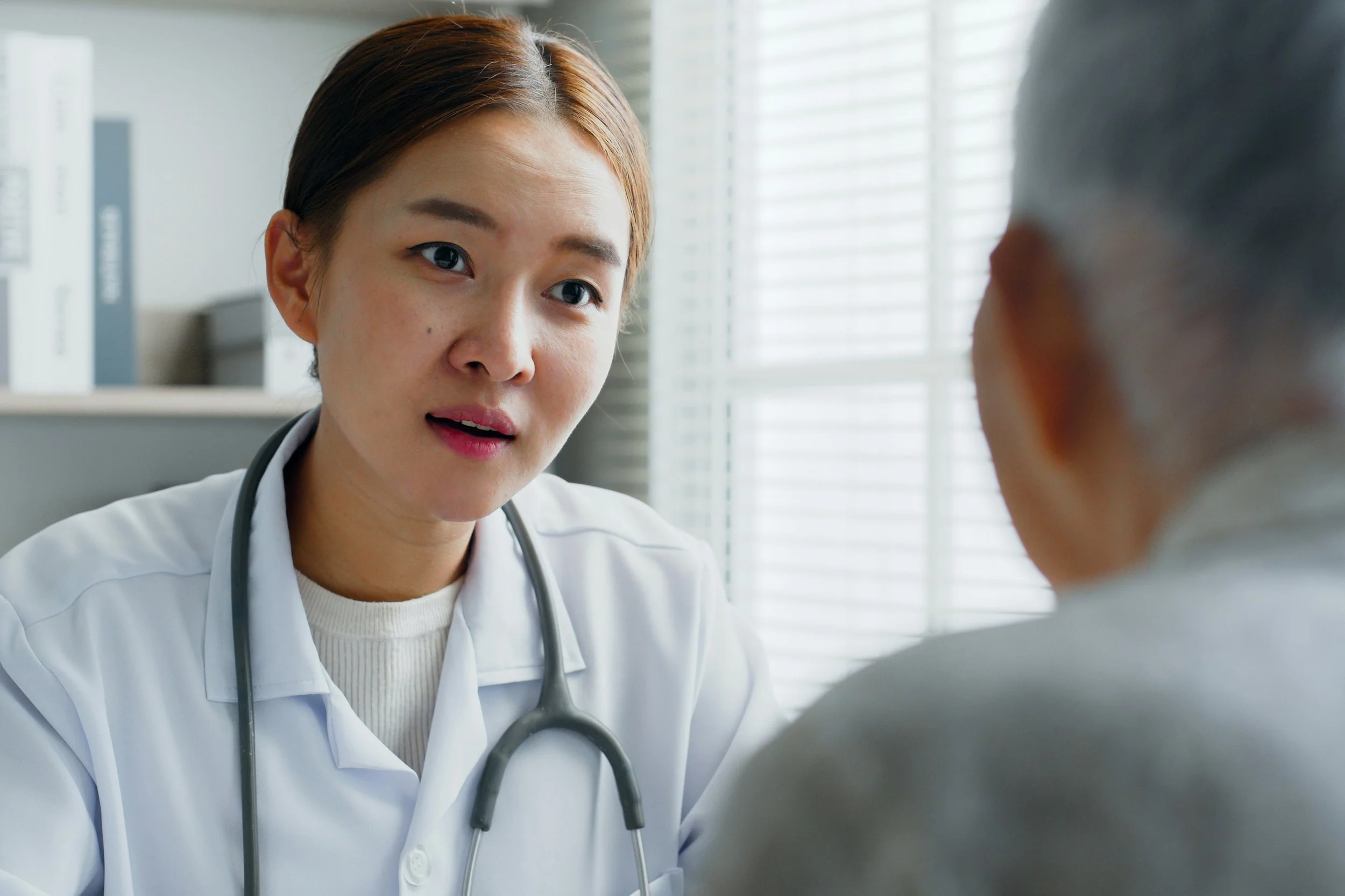A female doctor speaking with a patient in a medical office.