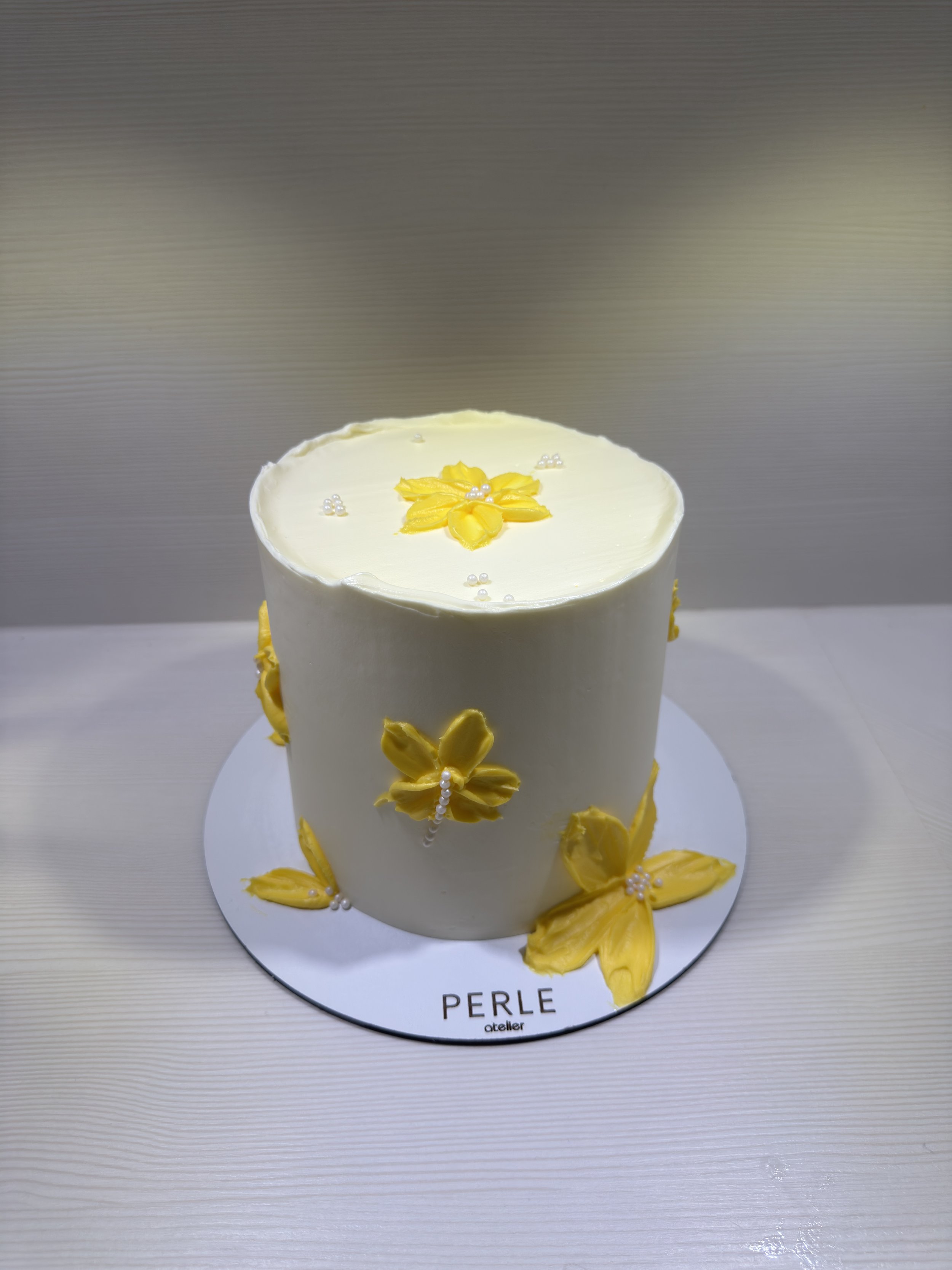 Gâteau blanc décoré avec des fleurs jaunes en crème au beurre