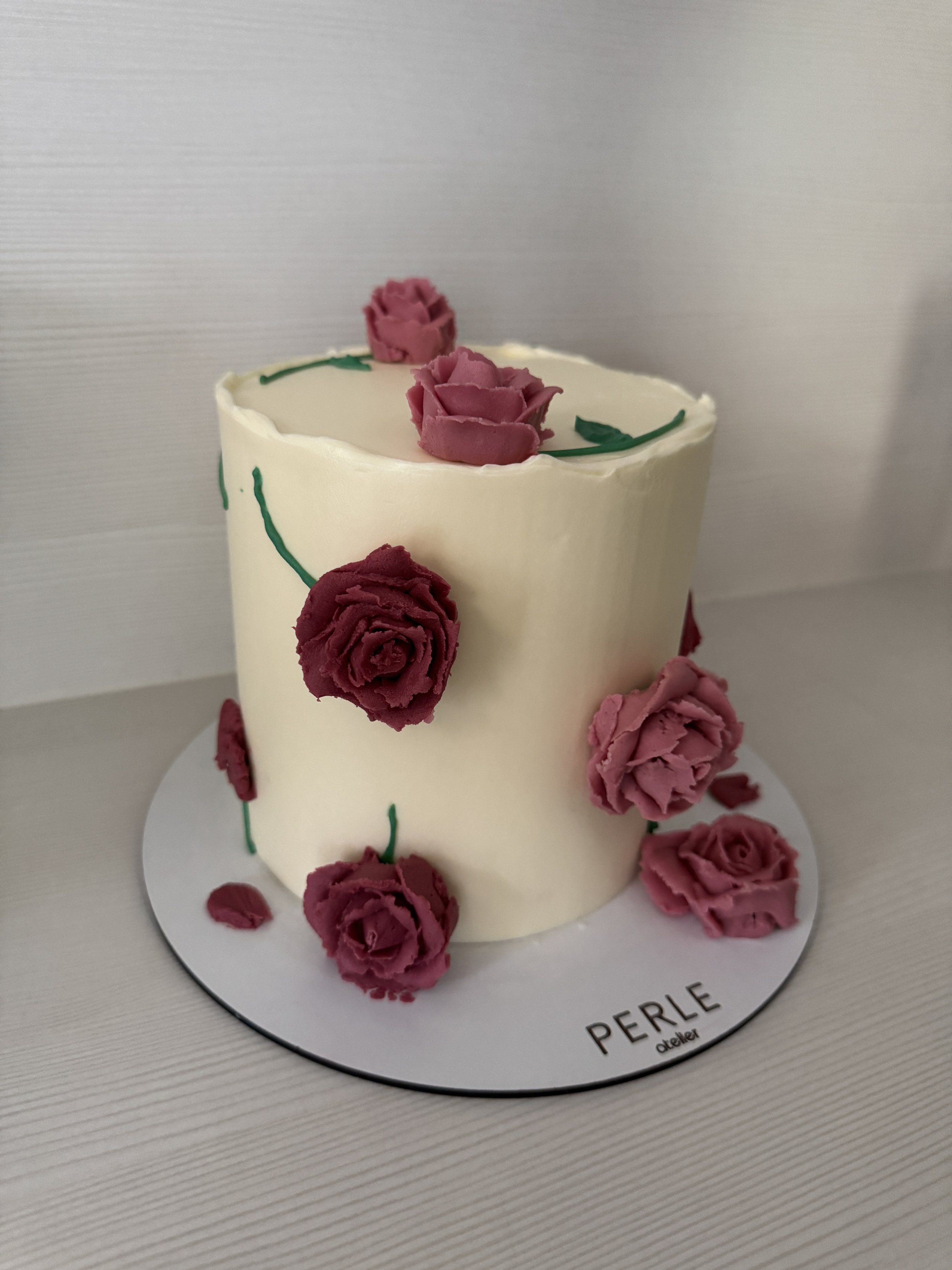 Gâteau blanc décoré de roses en crème au beurre roses et rouges et de lignes vertes faites à la main