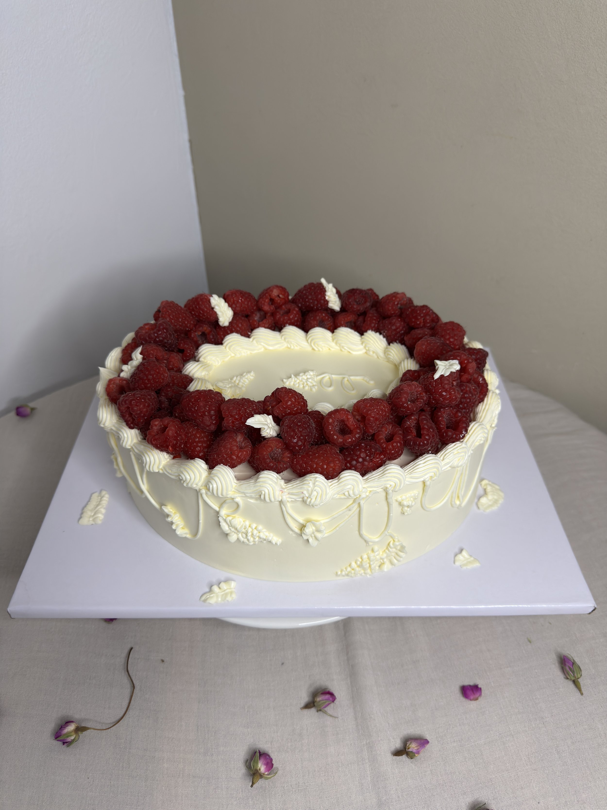 Gâteau rond décoré de framboises et de crème au beurre