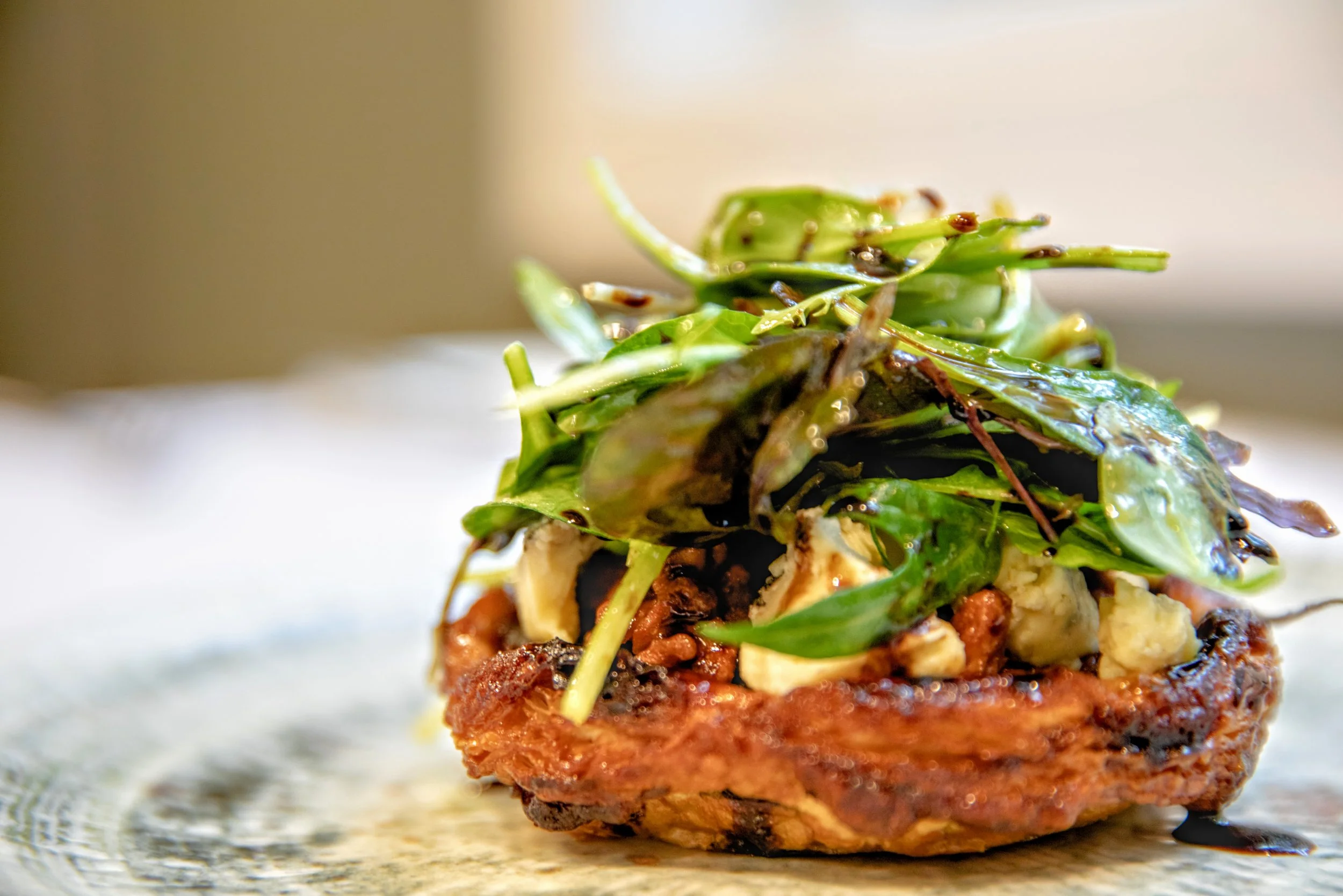 Caramelized shallot tart with creamy blue cheese, candied walnuts and aged balsamic, with a small salad on top. 