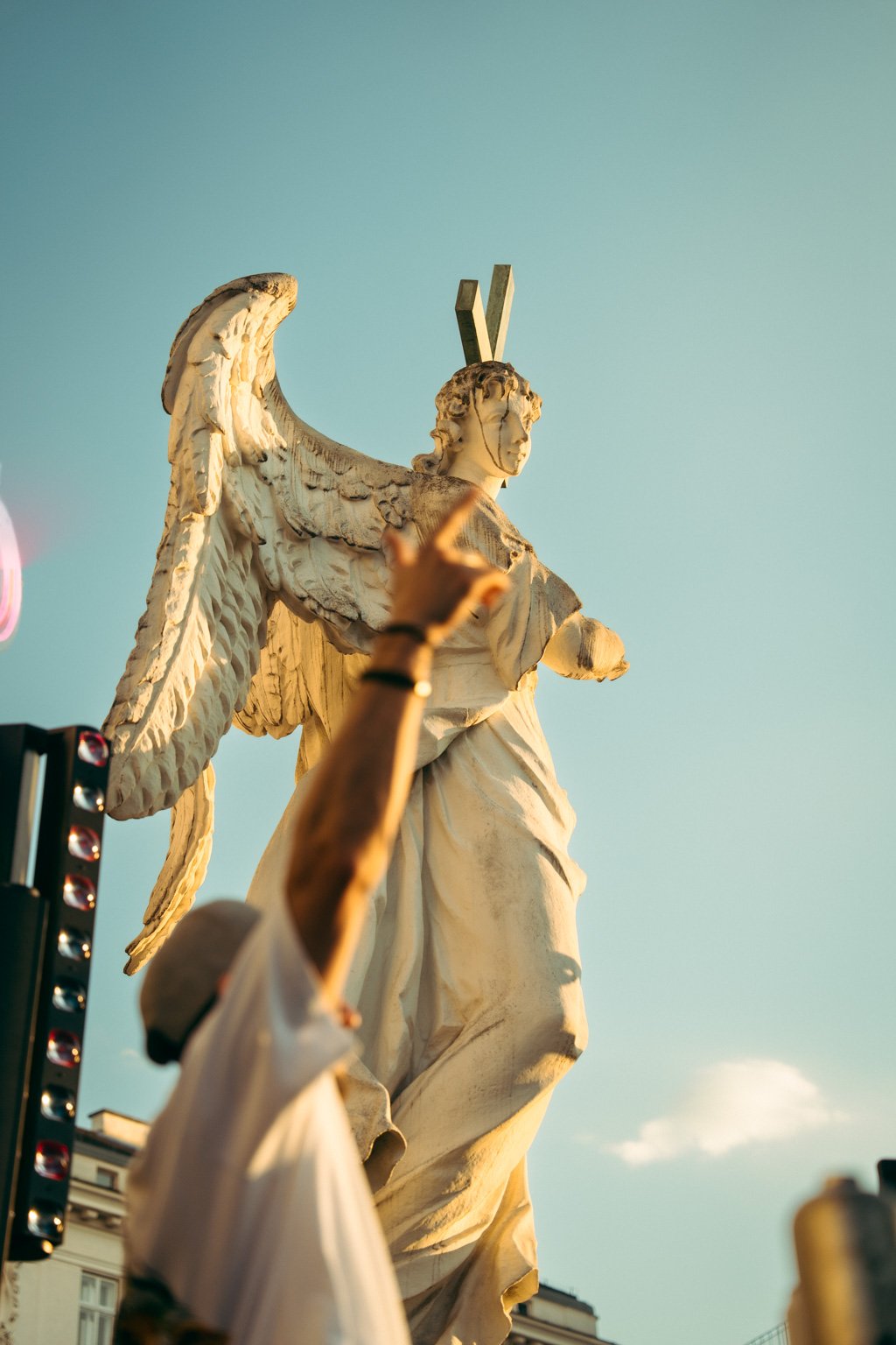 Eine große Statue einer weiblichen Figur mit Flügeln, die in der Luft schwebt, während die Sonne im Hintergrund scheint.