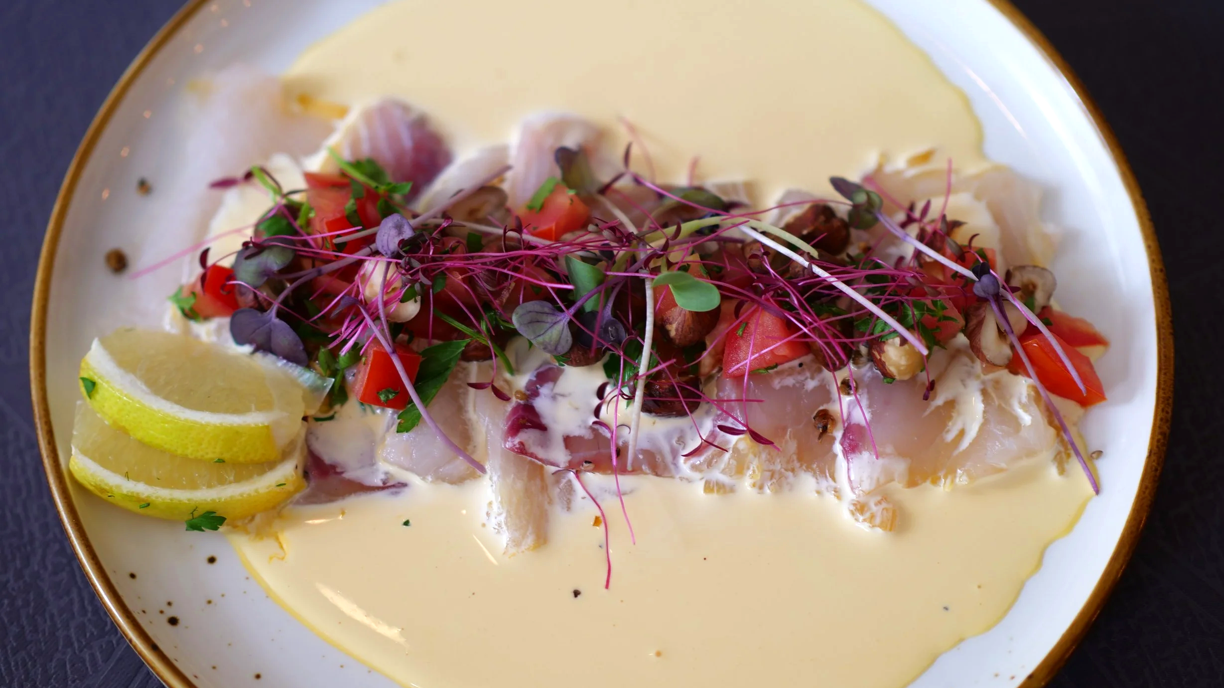Poisson cru avec citron, légumes frais, microgreens et sauce dans une assiette blanche, Tapas