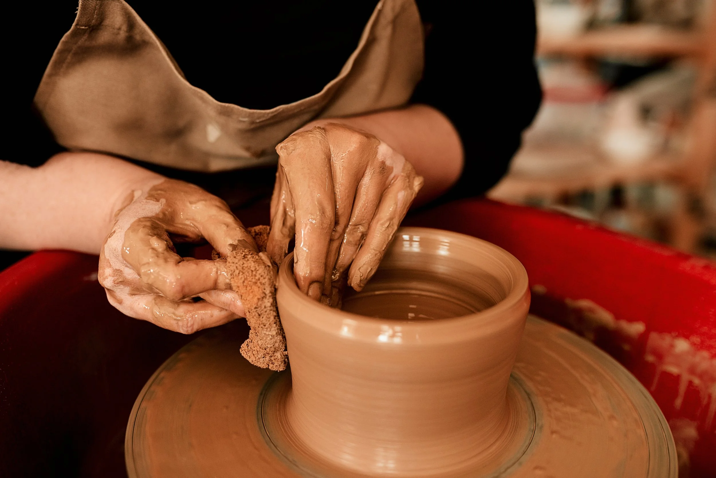 Close-up of a person shaping wet clay on a pottery wheel.