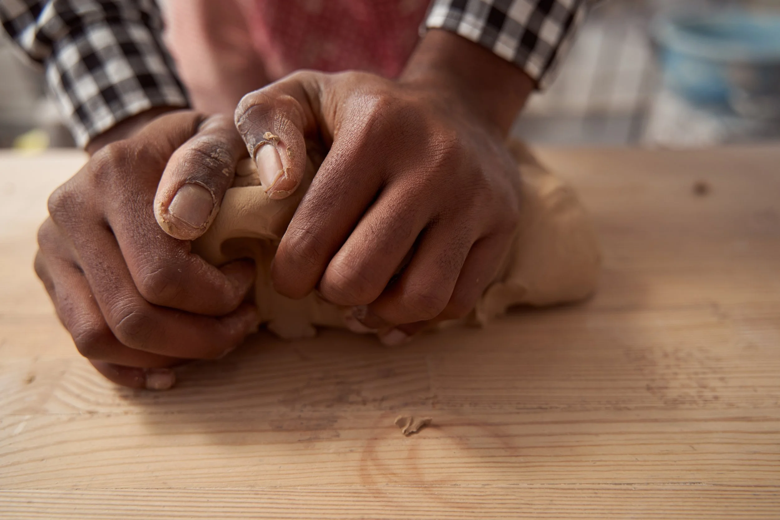 Close-up of two hands, one dark-skinned and one light-skinned, clasped together on a wooden surface, with a blurred background.