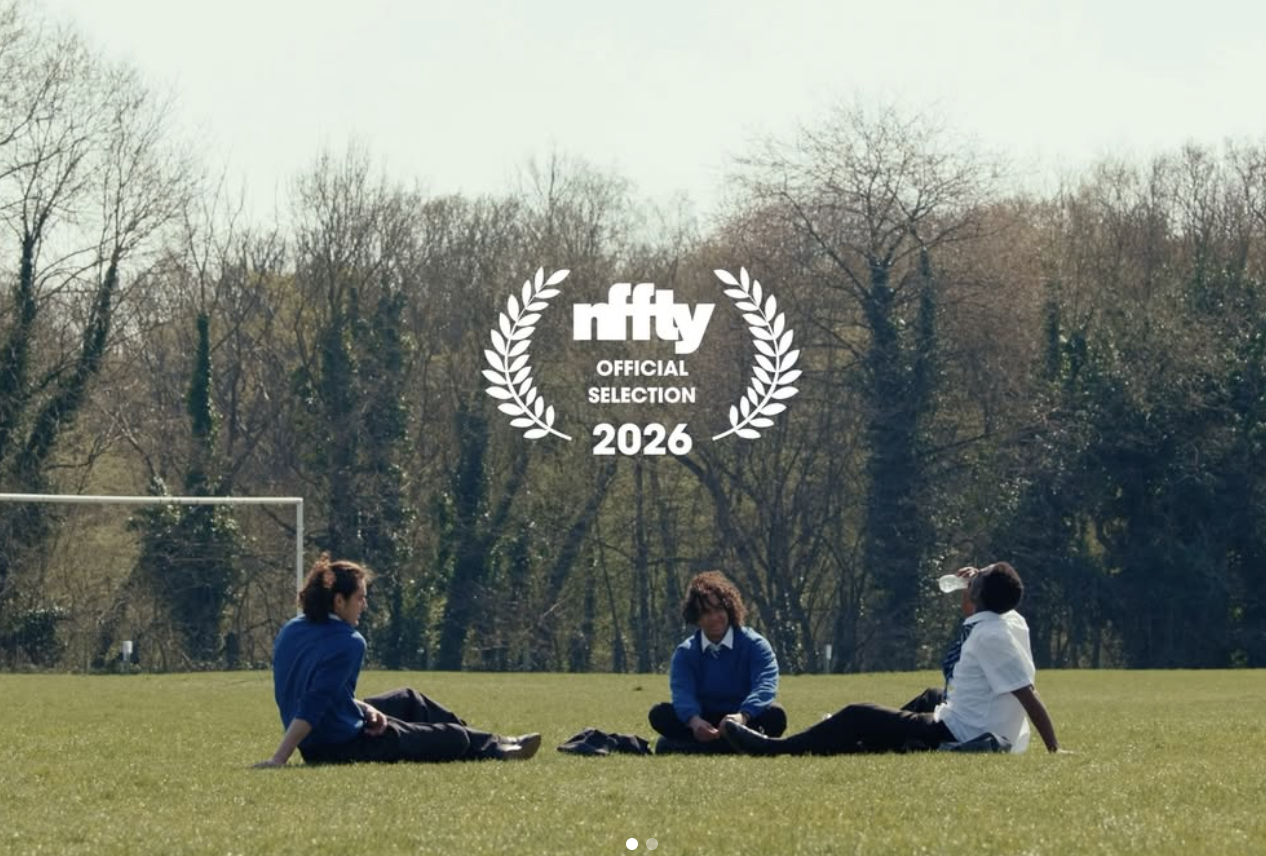 Three students in school uniforms sitting on a grassy field with bare trees in the background, appearing to be in a schoolyard or park, with an overlay of the Nifty Official Selection 2026 logo.