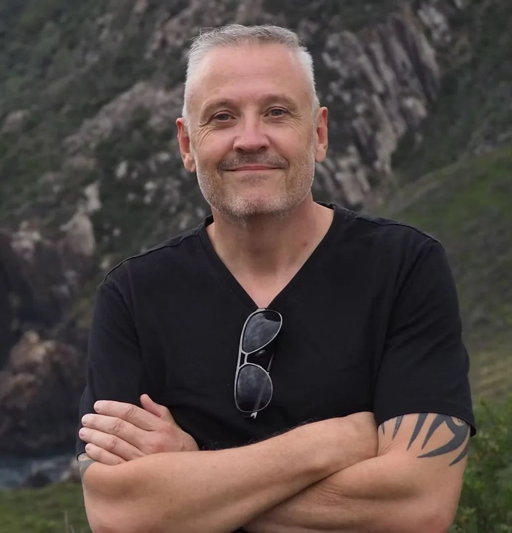 Image of Gary standing with his arms crossed and smiling at the camera
