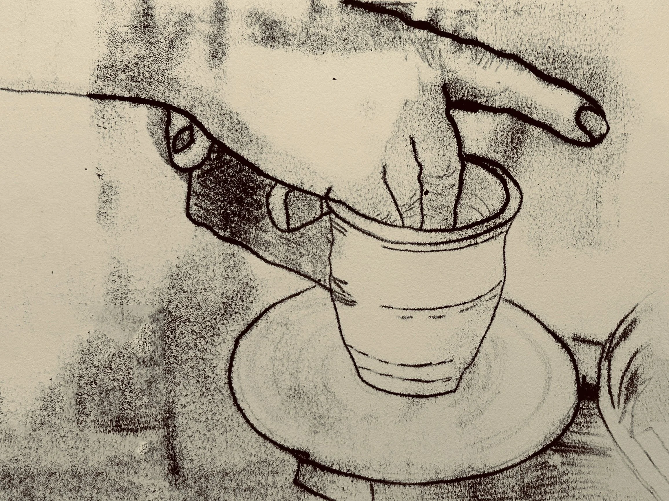 Two hands refine a ceramic cup on the pottery wheel.