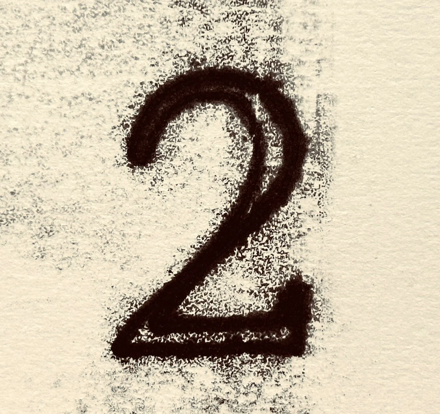 A hand-drawn black ink symbol resembling a lowercase 'e' with a triangular base on a piece of paper.