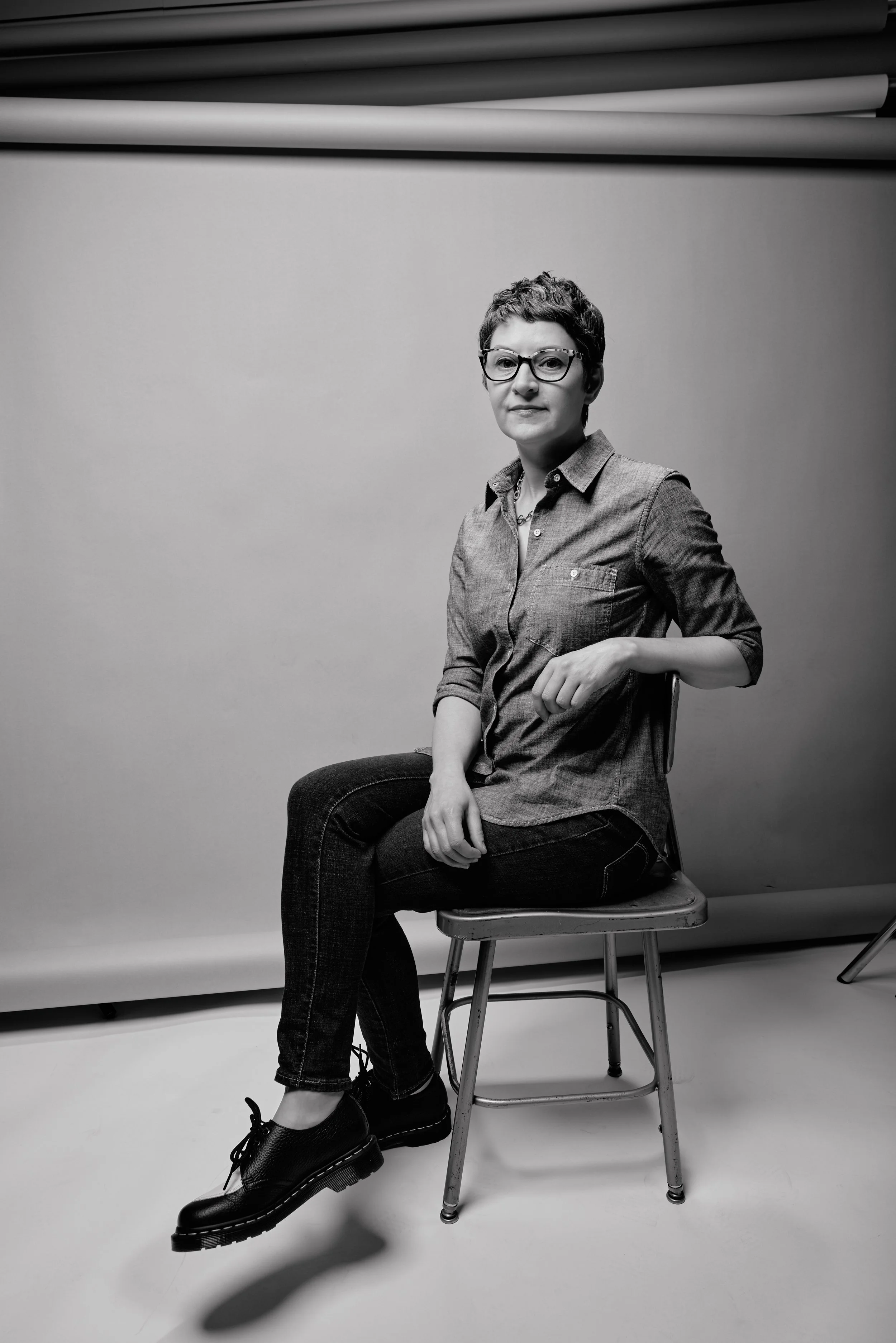 Artist and coach sits in a chair in a photography studio.