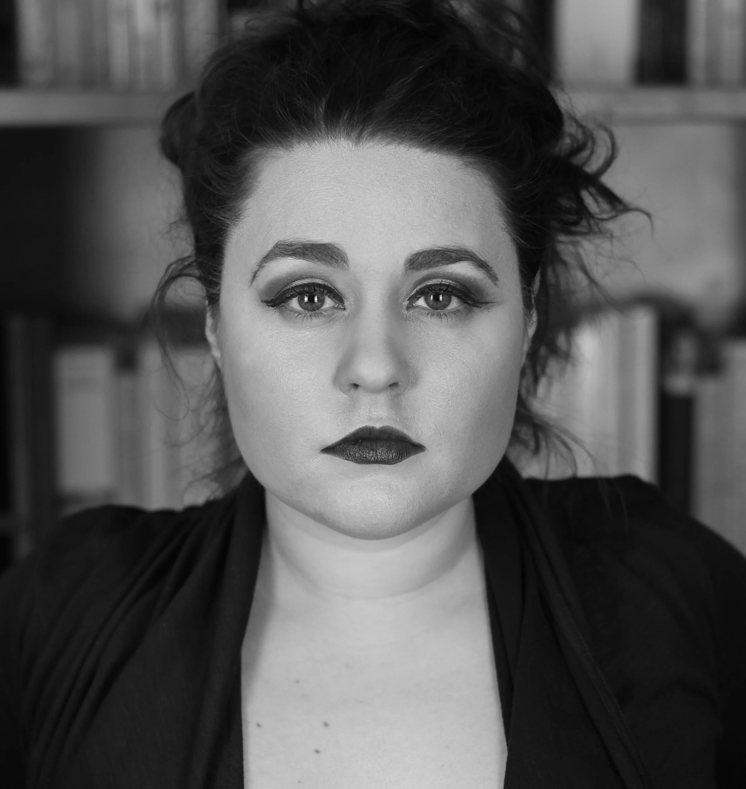 Black-and-white close-up portrait of a woman with dark hair, winged eyeliner, and dark lipstick.