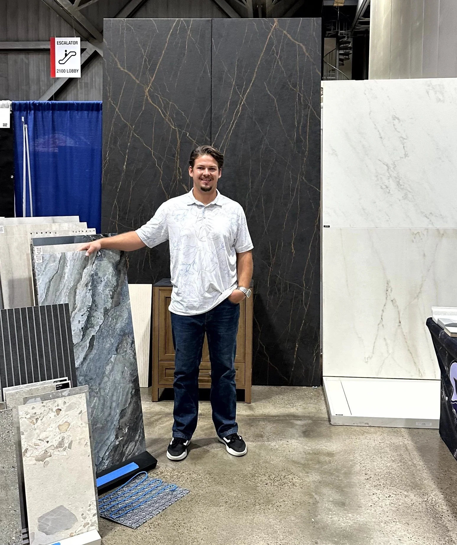 Dash inside a store in front of large Dekton slabs and tile samples at a recent Overland Park home show.