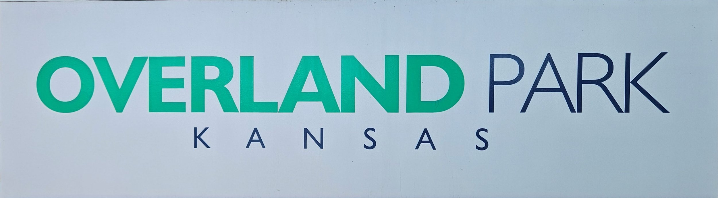 Sign that reads 'Overland Park Kansas' in green and blue letters.