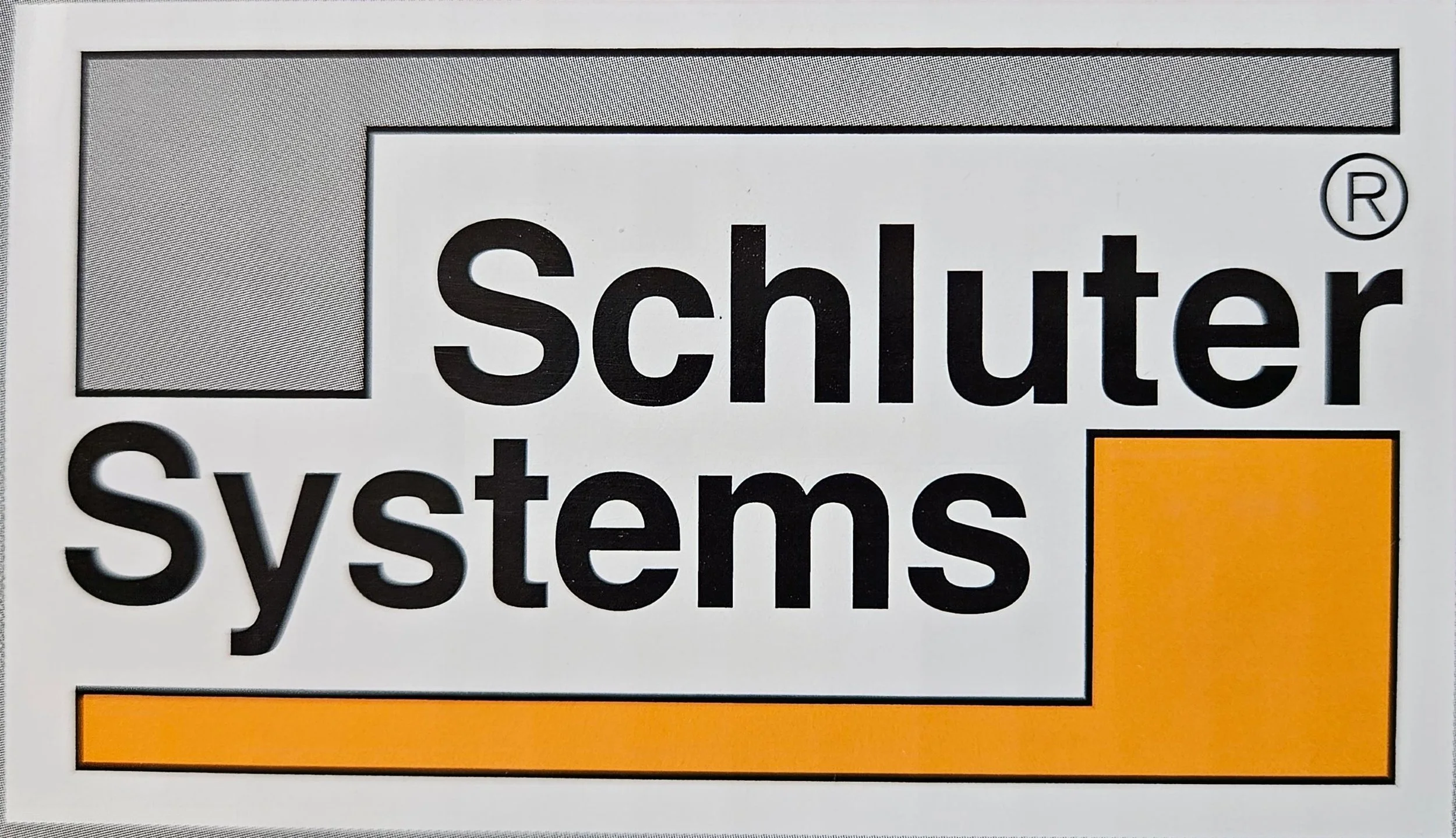 Close-up of a Schletter Systems logo, including the company name and a registration symbol on a gray and white background with an orange detail.