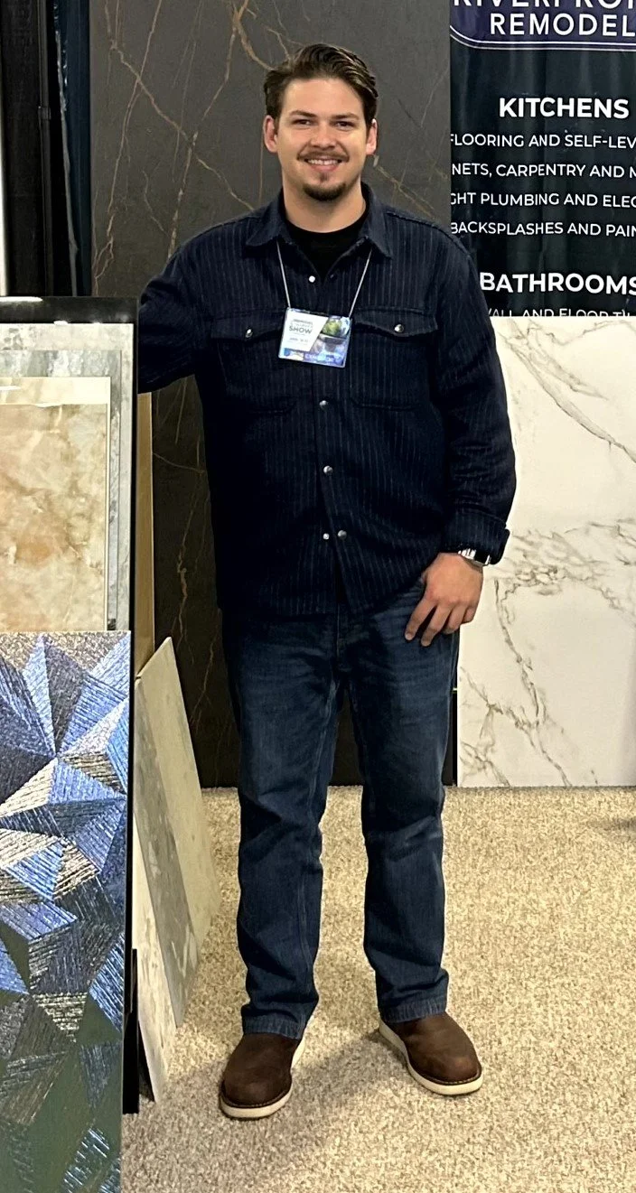 Dash Farr at the Home Show both in Kansas City Missouri. Behind him are large Dekton marble slabs and tiles and a sign promoting remodeling services for kitchens and bathrooms.