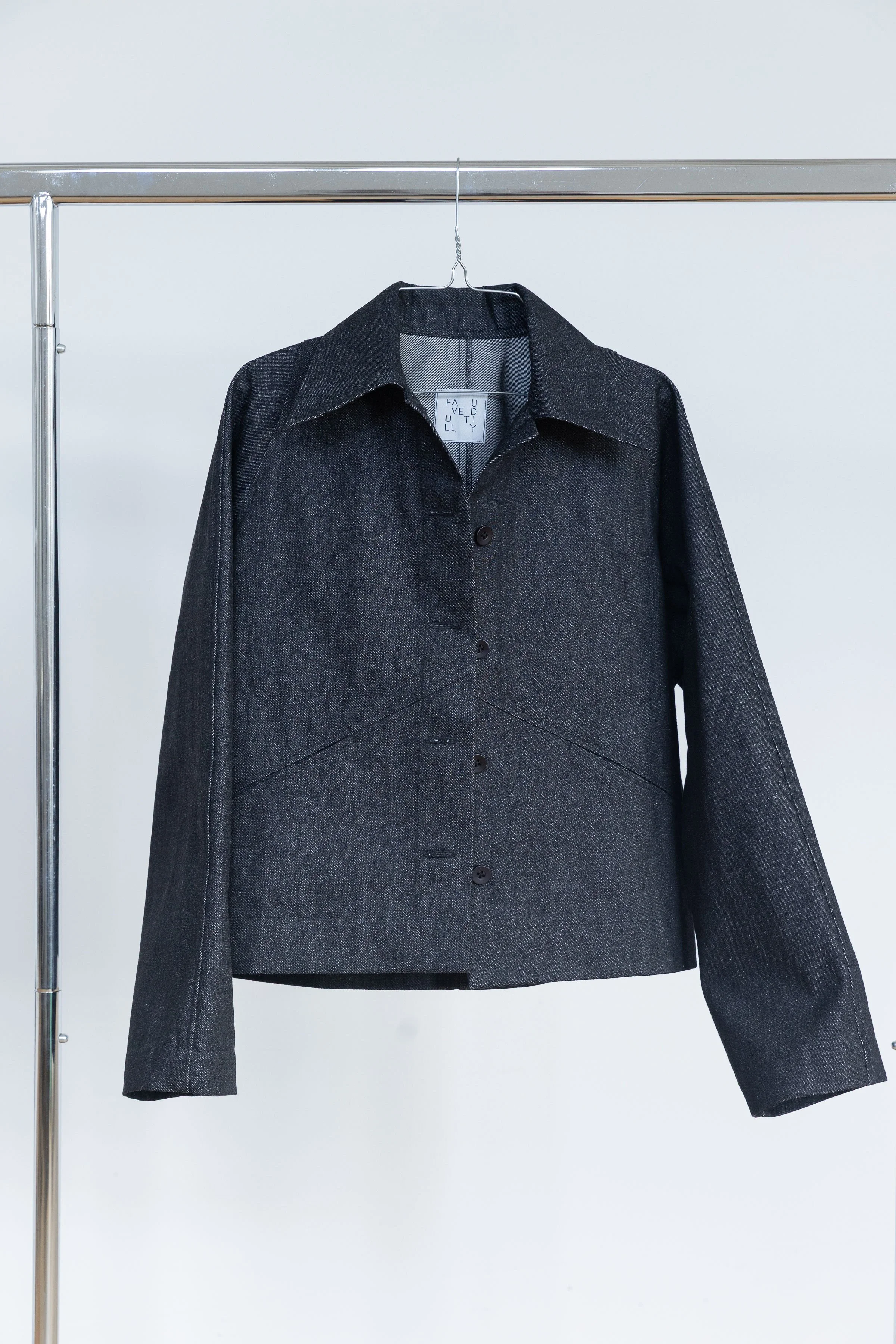 Veste en denim sombre suspendue sur un portemanteau en métal