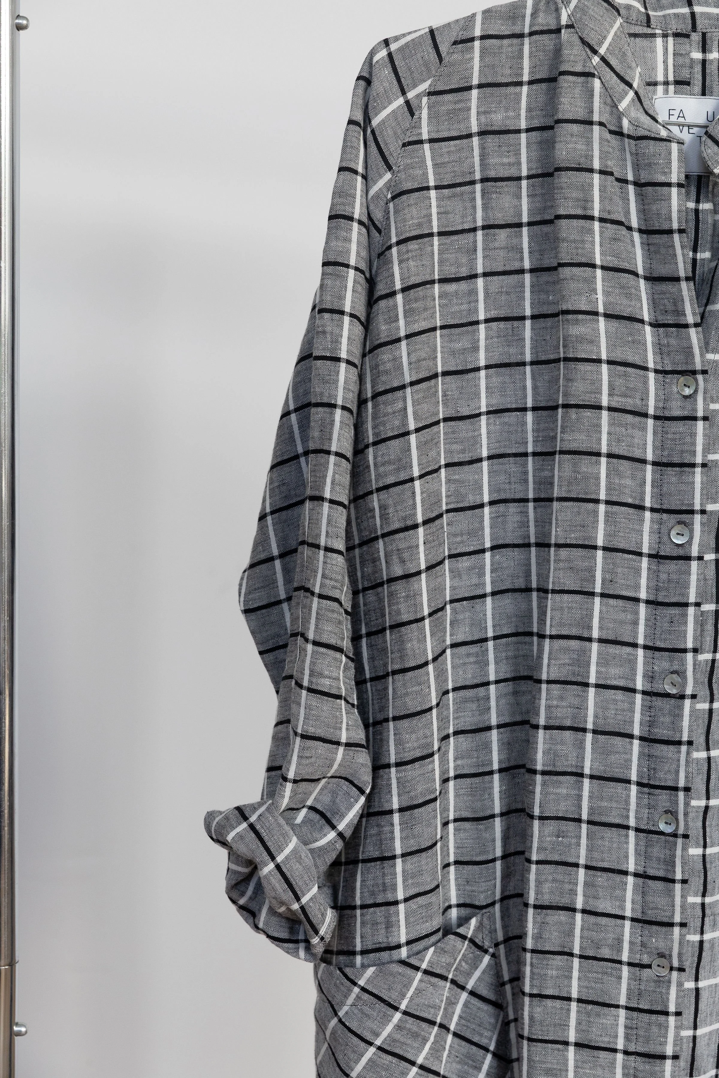 Chemise en tissu gris à motifs de rayures noires, blanches et lunettes, avec boutons à l'avant.