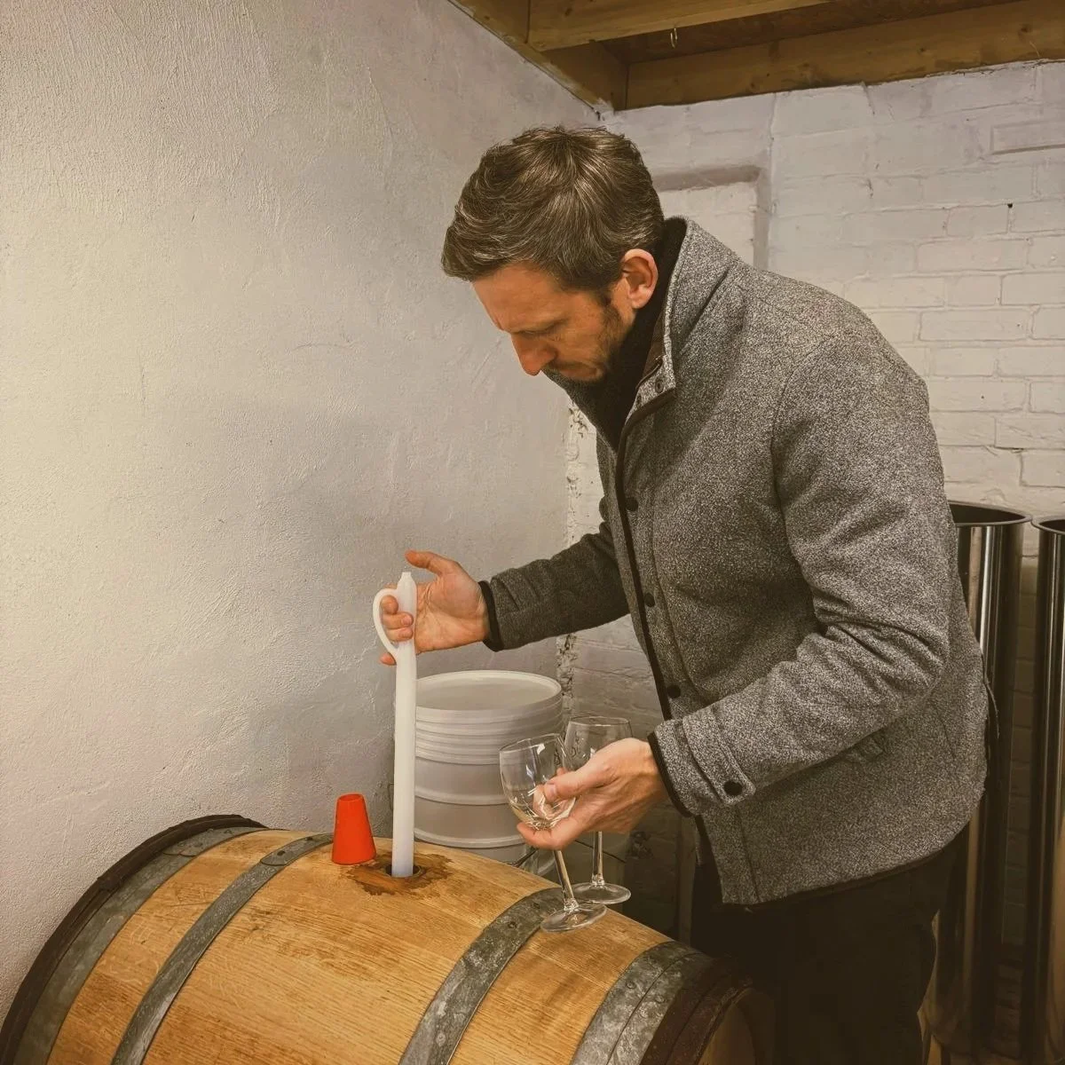 A man filling a wine glass from a candle holder on a wine barrel during a wine tasting event.