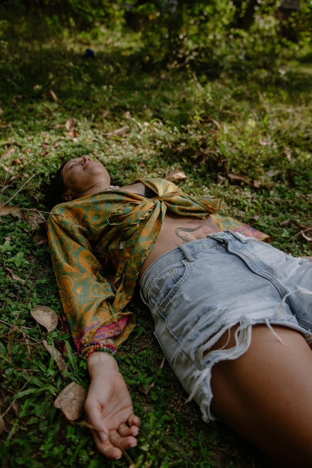 Caro resting on the forest floor during an outdoor breathwork and mindfulness session in nature.