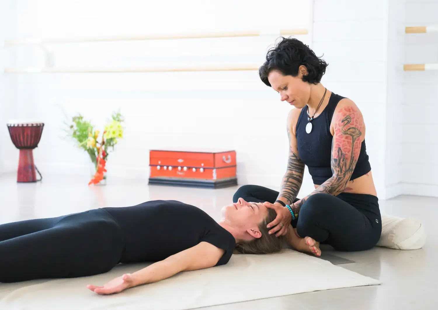 Caro performing ThaiVedic bodywork, cradling client's head on floor in bright Berlin studio