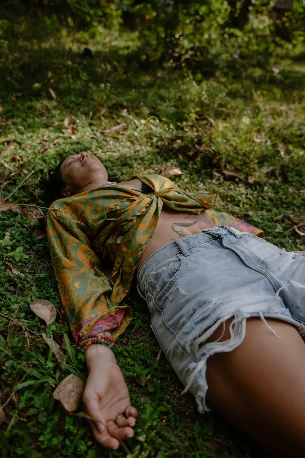 Caro resting on the forest floor during an outdoor breathwork and mindfulness session in nature.