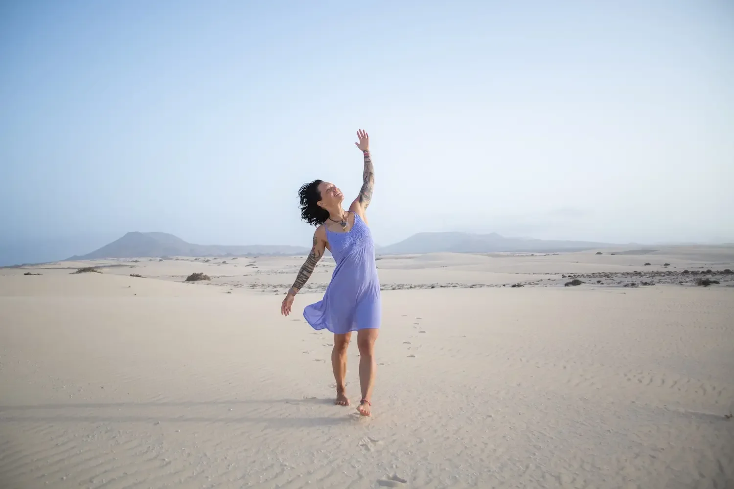 Woman moving freely and joyfully in a peaceful desert landscape.