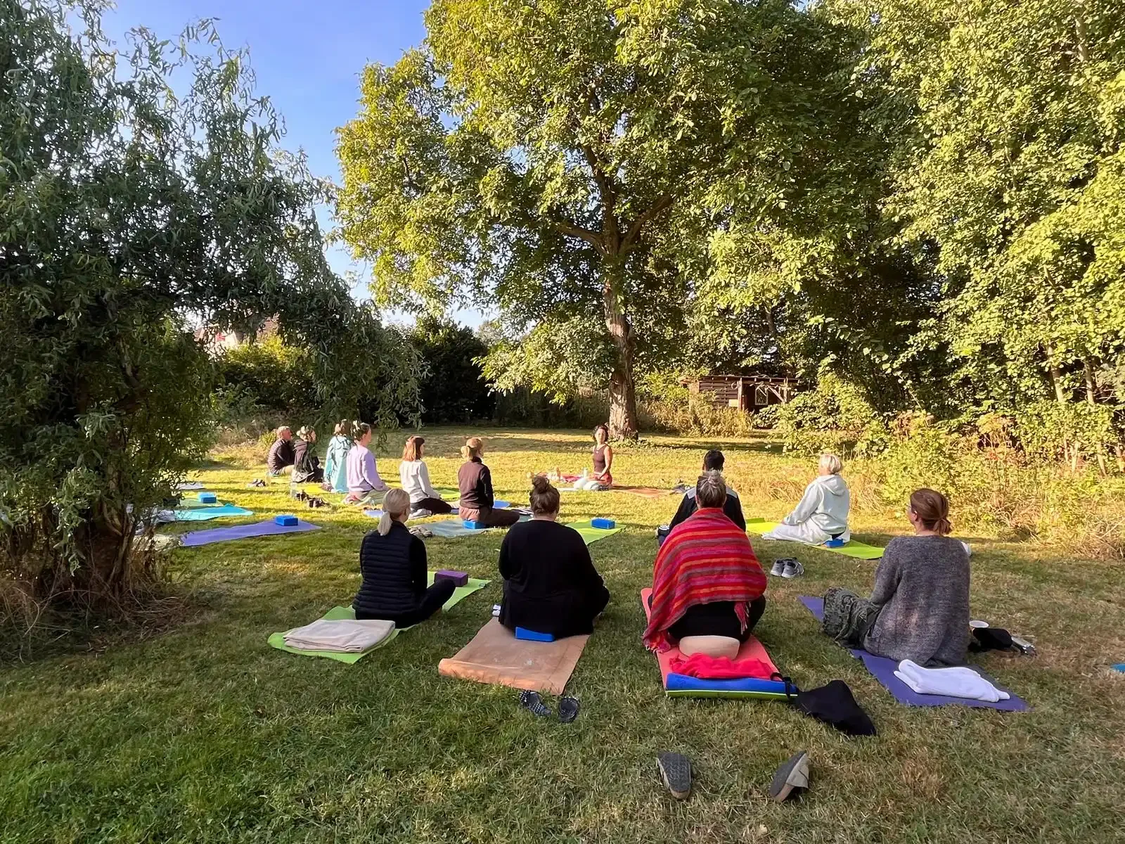 Participants practicing a group meditation during a yoga retreat in a peaceful, sunlit garden.