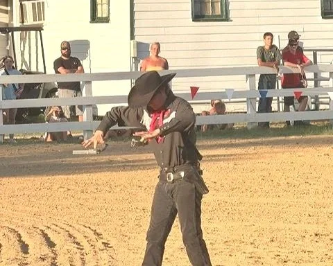 Person dressed as a cowboy riding a mechanical bull at an outdoor event.